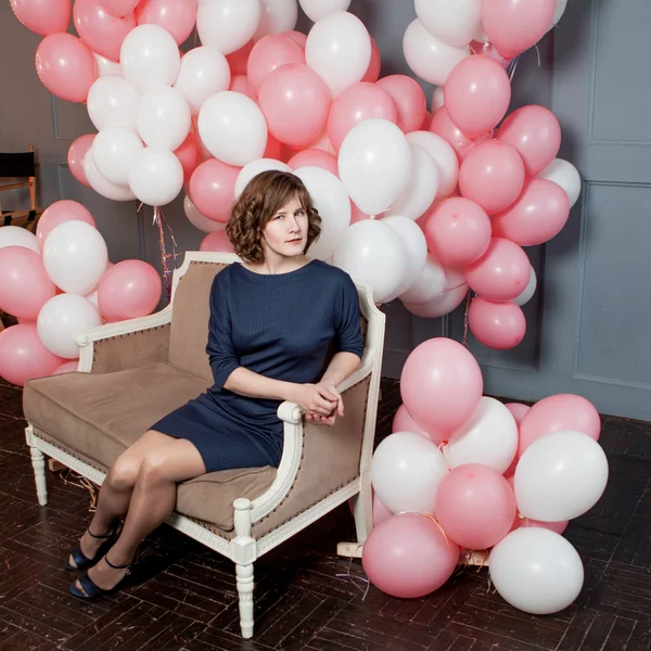 Jonge vrouw zittend op de Bank in een kamer vol van Luchtballons Opblaasbare — Stockfoto