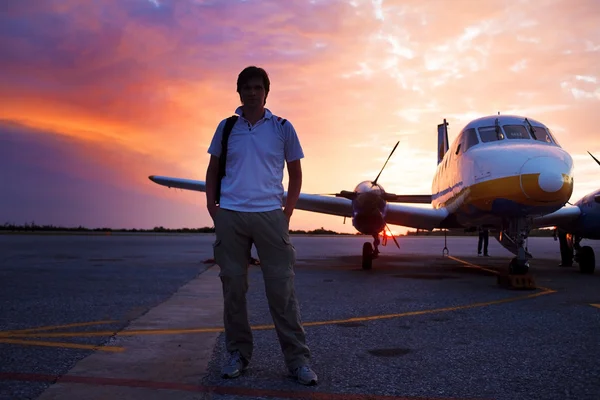 Young man on the runway in background of a small private plane — Stok fotoğraf