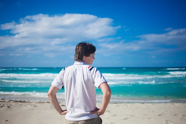 Handsome young man  against bright beach background, relaxes — Stock fotografie