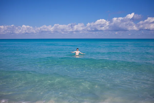 Поднимая руки человек плавает в море, на расстоянии — стоковое фото