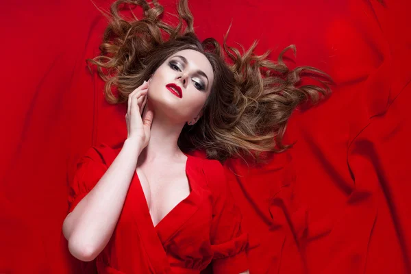 Mulher de vestido vermelho posando com tecido ondulado, horizontalmente — Fotografia de Stock