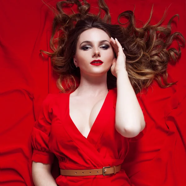 Mulher de vestido encontra-se em um fundo vermelho — Fotografia de Stock