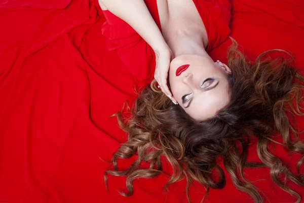 Woman in dress  lies on a red background — 스톡 사진