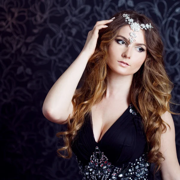 Beautiful girl  with long brown curled hair, dark background — Stock Photo, Image