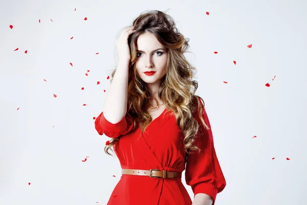 Fashion photo of young magnificent woman in red dress amid rose petals — Stock Photo, Image