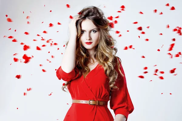 Fashion photo of young magnificent woman in red dress amid rose petals — Stock Photo, Image