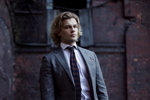 Szürke öltönyt, üzleti stílusban, a falon háttérben álló fiatal üzletember — Stock Fotó