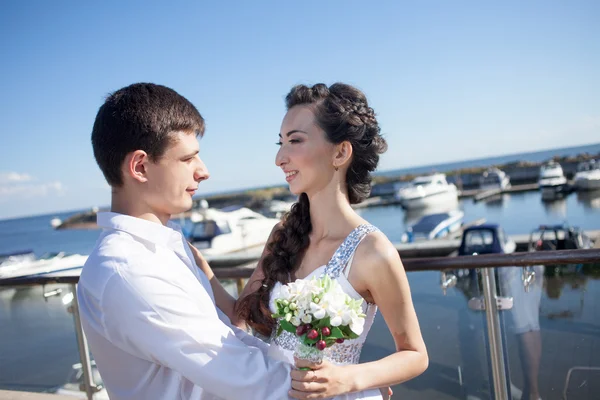 Nevěsta a ženich na pozadí yacht club, mladý šťastný pár pohledu na sebe — Stock fotografie