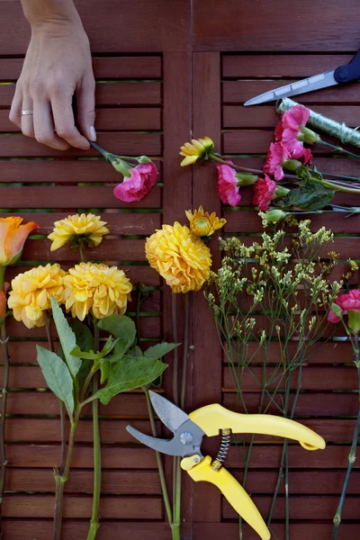 Flores y herramientas sobre la mesa, floristería lugar de trabajo, bodegón vista superior — Foto de Stock