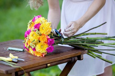 Genç güzel kadın çiçekçi. Kız parkta bir buket çizer. Açık