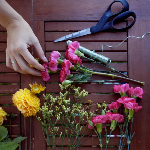 Fleurs et outils sur la table, lieu de travail fleuriste, nature morte vue de dessus — Photo
