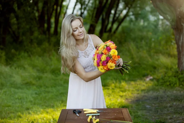 Jonge mooie vrouw bloemist. Het meisje in het Park trekt een boeket. Buiten — Stockfoto