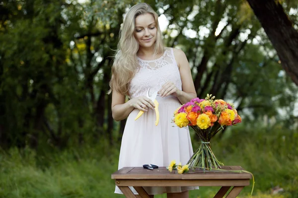 Joven florista hermosa mujer. La chica del parque dibuja un ramo. Exterior —  Fotos de Stock