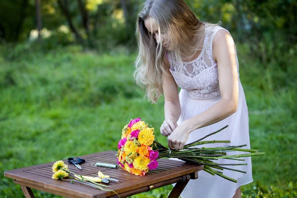 Mladá krásná žena květinářství. Dívka v parku nakreslí kytice. Venkovní — Stock fotografie