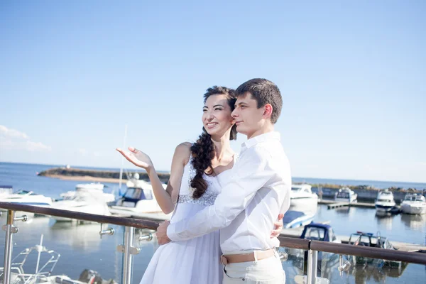 Bruid en bruidegom op de achtergrond van de jachtclub, jonge gelukkige paar naar links kijken — Stockfoto