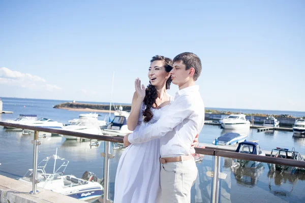 Bruid en bruidegom op de achtergrond van de jachtclub, jonge gelukkige paar naar links kijken — Stockfoto