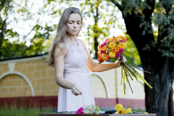 Jonge mooie vrouw bloemist. Het meisje in het Park trekt een boeket. Buiten — Stockfoto