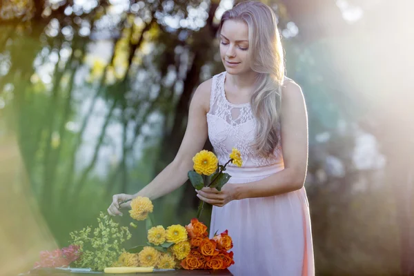 Jovem florista mulher bonita. A menina no parque desenha um buquê. Ao ar livre — Fotografia de Stock