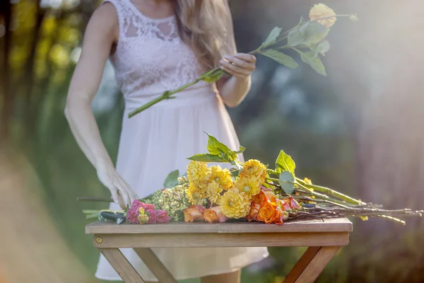 Mladá krásná žena květinářství. Dívka v parku nakreslí kytice. Venkovní — Stock fotografie
