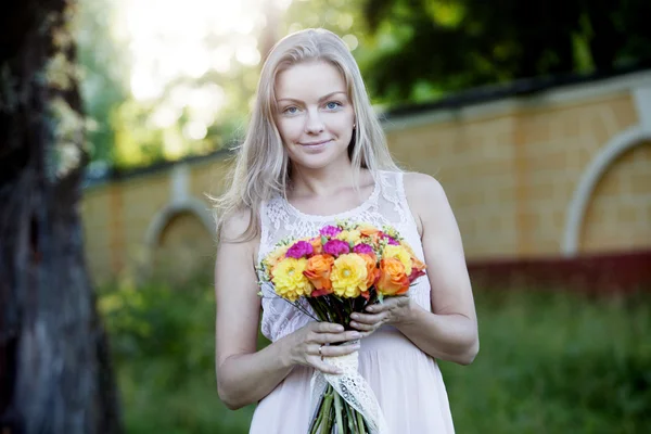 Jonge mooie vrouw met een heldere boeket van bloemen, buitenshuis, warme zonnige dag — Stockfoto