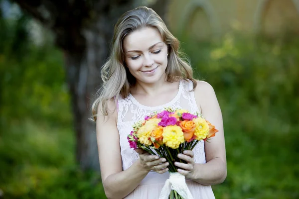 Young beautiful woman with a bright bouquet of flowers, outdoors, warm Sunny day — Stock Photo, Image