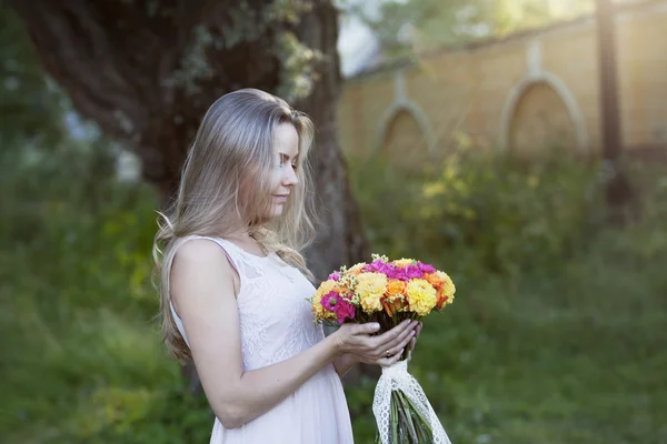 Joven hermosa mujer de perfil con un brillante ramo de flores, al aire libre, cálido día soleado — Foto de Stock