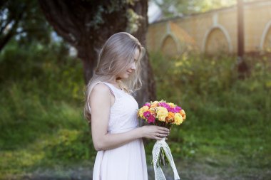 Profili ile parlak bir buket çiçek, açık havada, genç güzel kadın sıcak güneşli bir gün