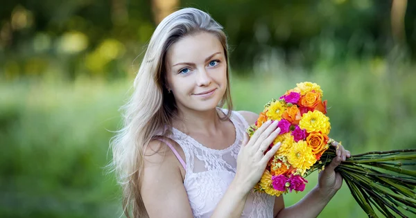 Joven hermosa mujer con un brillante ramo de flores, al aire libre, cálido día soleado —  Fotos de Stock