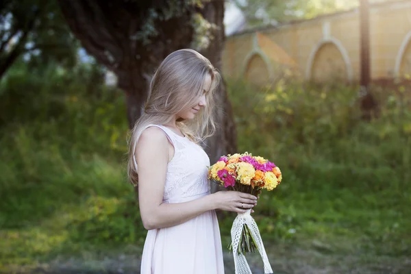 Mulher bonita nova no perfil com um buquê brilhante de flores, ao ar livre, dia ensolarado quente — Fotografia de Stock