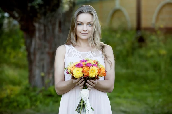 Mulher bonita nova com um buquê brilhante de flores, ao ar livre, dia ensolarado quente — Fotografia de Stock