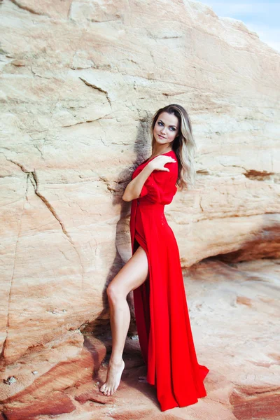 Frau im roten Kleid vor dem Hintergrund der Sandkarriere — Stockfoto