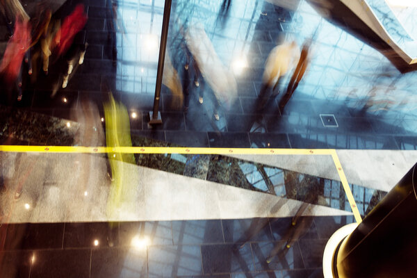 Люди в торговом центре, размытые следы движения, вид сверху. Мягкое размытие фона, темный стиль
