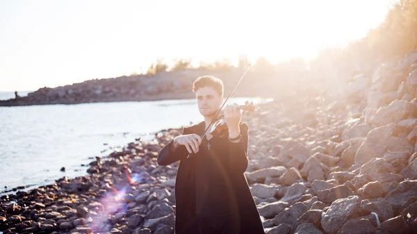 Violinist playing a violin,  young man plays on the background of  sea — Stock Photo, Image