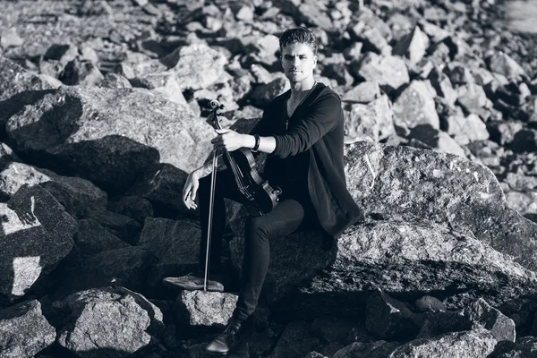 Hegedűművész játszik a hegedű, a fiatal ember játszik a háttérben a tenger, a fekete-fehér alakformálás — Stock Fotó