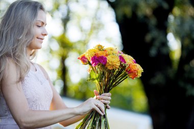 Genç güzel kadın çiçekçi. Kız parkta bir buket çizer. Açık