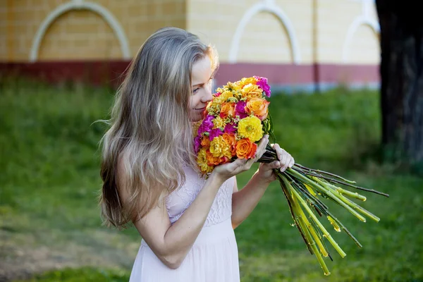 Jovem mulher bonita com um buquê brilhante, menina cheirando flores — Fotografia de Stock