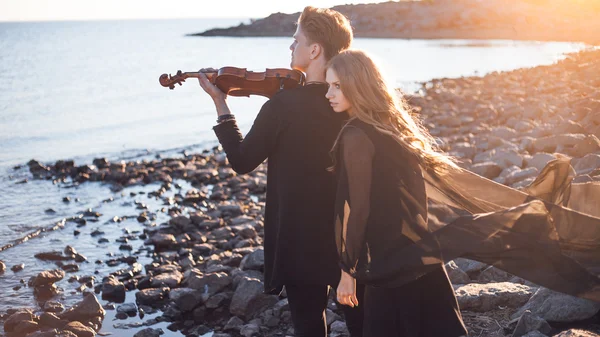 Violinist and girl,  young man plays on the background of  sea — Stock Photo, Image