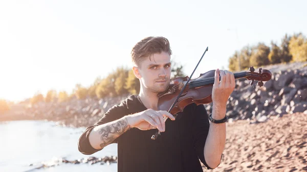 Violinist playing a violin,  young man plays on the background of  sea — Stock Photo, Image