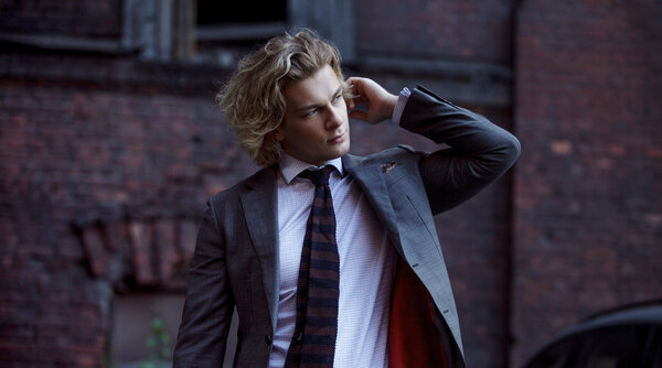 молодой бизнесмен в сером костюме, деловом стиле, портрет на фоне стены
