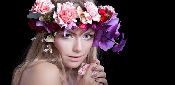 Portret jonge mooie vrouw in krans van bloemen, zwarte achtergrond — Stockfoto