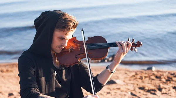 Violinist playing a violin,  young man plays on the background of  sea — Stock Photo, Image