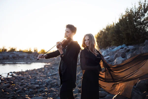 Violinist and girl,  young man plays on the background of  sea — Stock Photo, Image