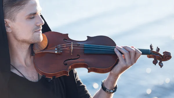 Violinist playing a violin,  young man plays on the background of  sea — Stock Photo, Image