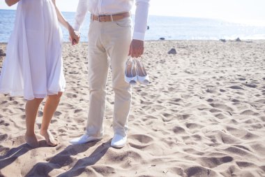 Sadece evli çift, ayak görüntülemek kumlu bir plaj üzerinde çalışan damat ayakkabı tutar.