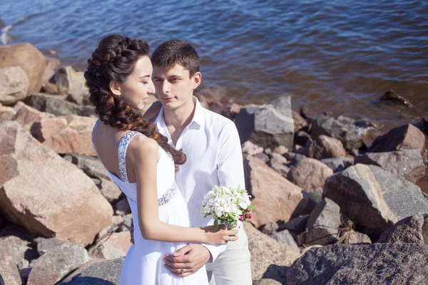 Prostě šťastný manželé na skalnaté pláži — Stock fotografie