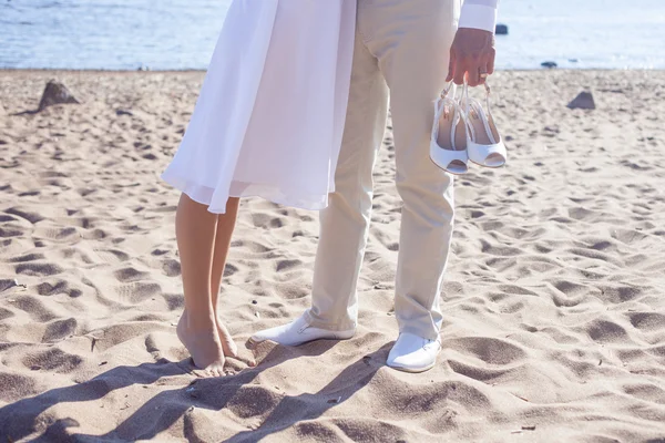 Couple marié courant sur une plage de sable, vue sur les pieds, marié tient des chaussures — Photo