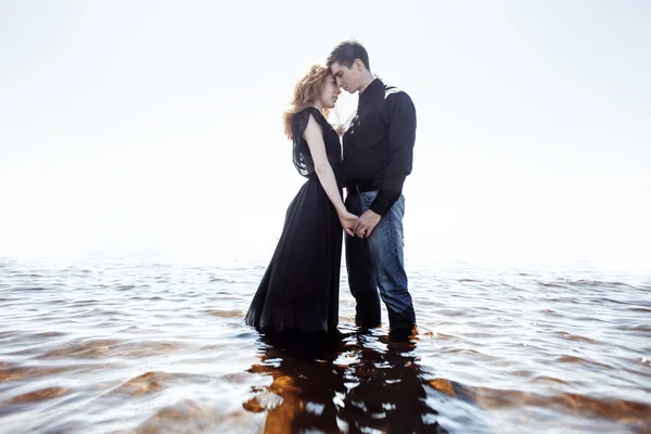 Beautiful young couple hugging standing in the sea, photo colorization effects — Stock Photo, Image