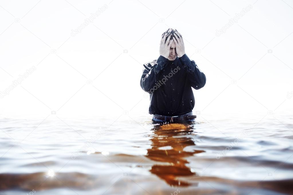 Young man experiencing the pain and disappointment, water through fingers