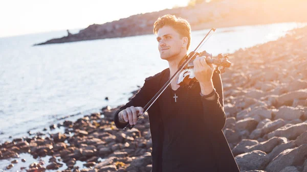 Violist spelen een viool, een jonge mens speelt op de achtergrond van de zee — Stockfoto