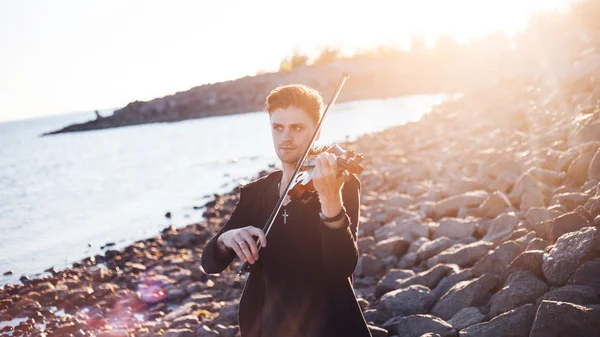 Скрипаль грає на скрипці, молодий чоловік грає на фоні моря — стокове фото